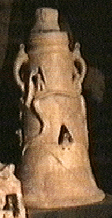 cylindrical stand with serpents crawling up and openings cut in the walls
