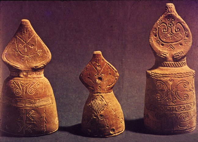 three figurines with long skirts and incised decorations