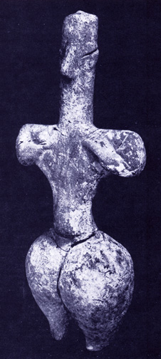 standing female figurine with rounded hips and hands to breasts