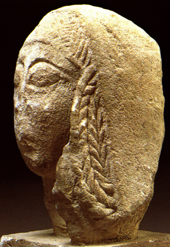 archaic-featured woman's head with large eyes and elaborate braids covered by mantle