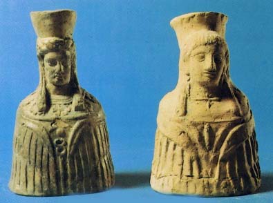 two clay figurines of women, waist-high, with winged mantles and high headdresses