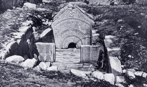 carved flat stone in peaked shape, with small semicircular entrance set low