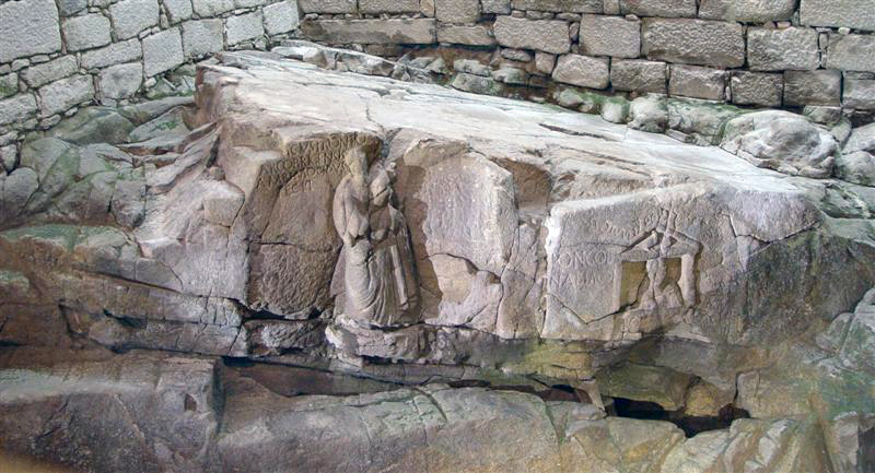 large sculptured stone mass resting within stone masonry enclosure