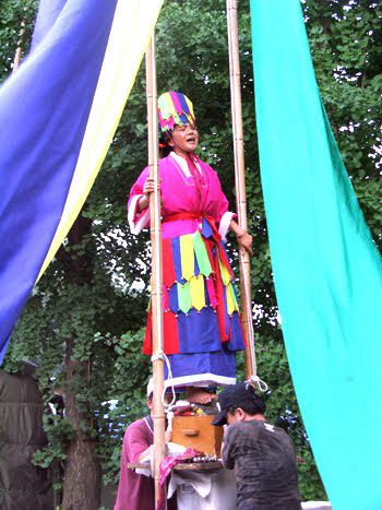 shaman standing aloft holding two long poles