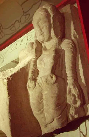stone maiden with long braids hung with ornaments