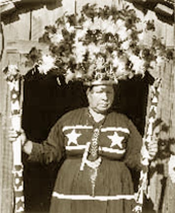 dreamer in tall feathered headdress standing with medicine poles